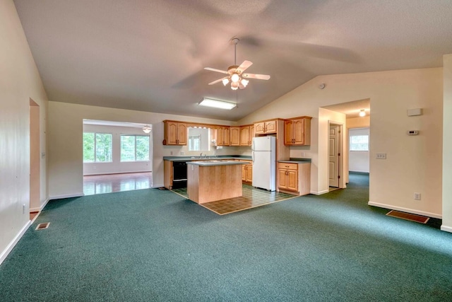 kitchen featuring ceiling fan, vaulted ceiling, white refrigerator, and dark tile patterned floors