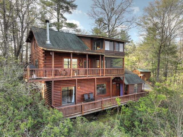 back of house with log exterior and a shingled roof