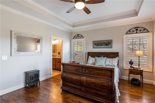 bedroom featuring a wood stove, baseboards, a raised ceiling, and dark wood finished floors