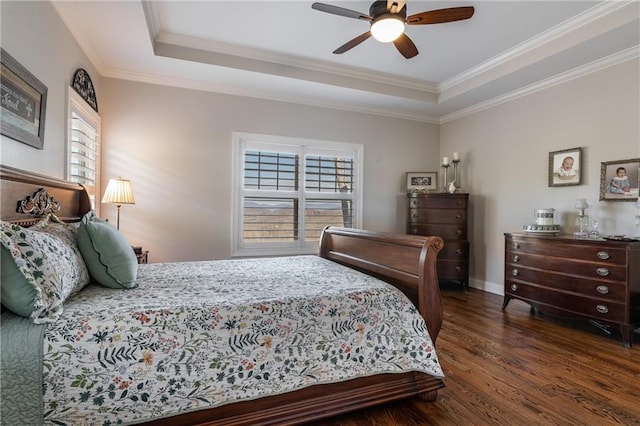 bedroom with a tray ceiling, dark wood finished floors, a ceiling fan, and crown molding