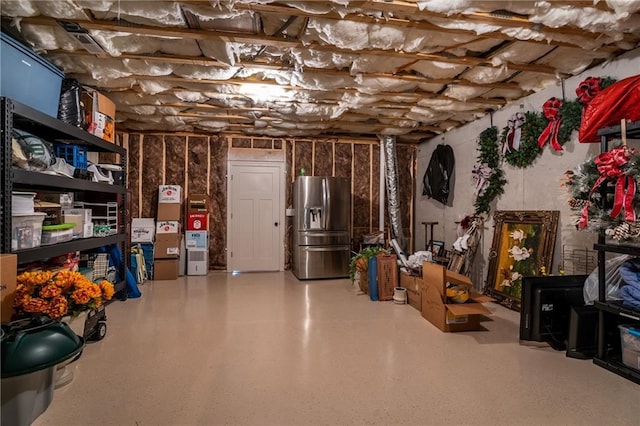 unfinished below grade area featuring stainless steel refrigerator with ice dispenser