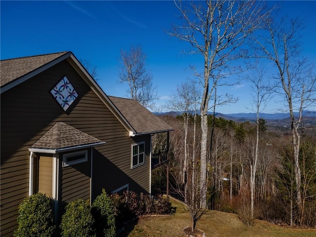 view of side of home with a shingled roof and a mountain view