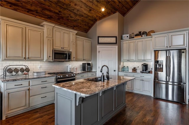 kitchen with wooden ceiling, a sink, appliances with stainless steel finishes, light stone countertops, and a center island with sink