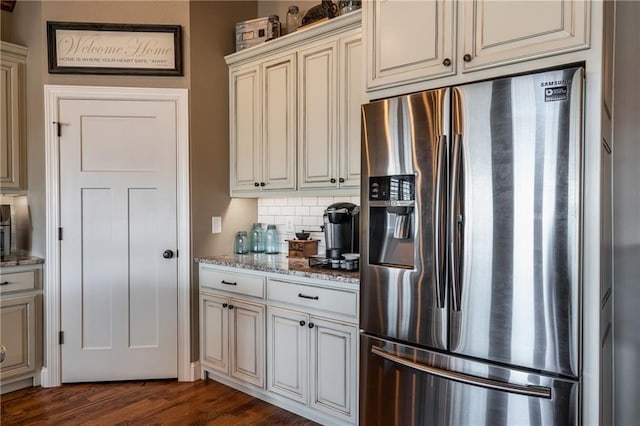 kitchen featuring backsplash, dark wood finished floors, light stone countertops, and stainless steel fridge with ice dispenser