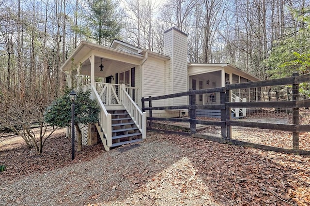 view of front of house with fence, a chimney, and stairs