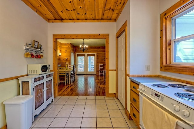 kitchen with french doors, light tile patterned floors, wooden ceiling, an inviting chandelier, and white appliances