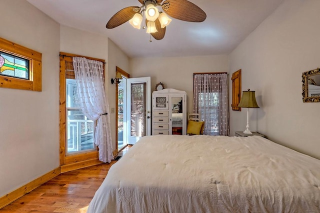 bedroom with access to outside, multiple windows, baseboards, and wood finished floors