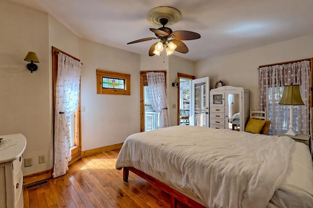 bedroom featuring ceiling fan, visible vents, baseboards, access to outside, and hardwood / wood-style floors