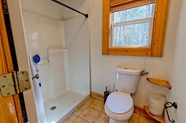 bathroom with a stall shower, tile patterned floors, toilet, and baseboards