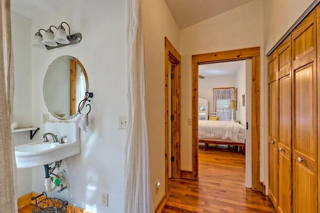 hallway featuring a sink, hardwood / wood-style flooring, and baseboards