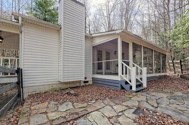 view of home's exterior featuring a sunroom, a chimney, and fence