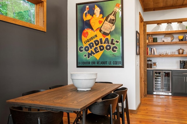 bar with gray cabinetry, light wood-type flooring, wood ceiling, and beverage cooler