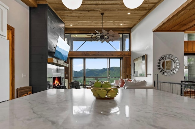 dining space with a fireplace, ceiling fan, and wooden ceiling