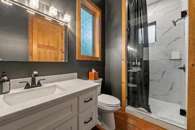 bathroom with toilet, a shower with door, vanity, and hardwood / wood-style flooring