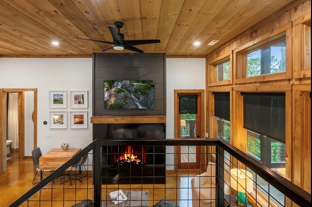 interior space featuring tile patterned floors, ceiling fan, a large fireplace, and wooden ceiling