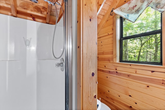 bathroom featuring wooden walls and a shower with door