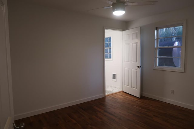 spare room with ceiling fan, dark wood-type flooring, and a wealth of natural light