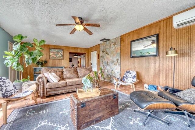 living room with ceiling fan, wood walls, a textured ceiling, and a wall mounted AC