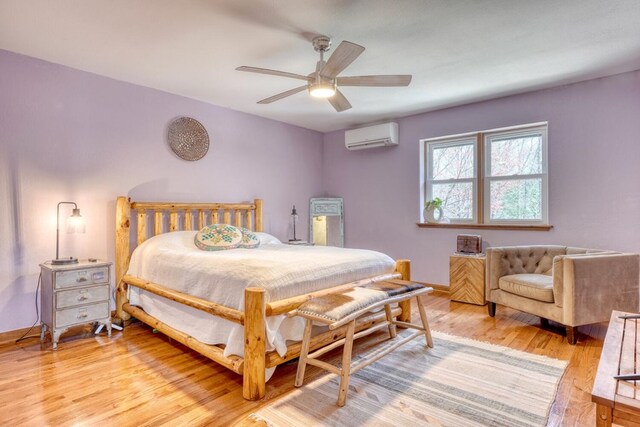 bedroom featuring a wall mounted AC, ceiling fan, and light hardwood / wood-style flooring