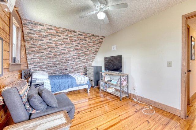 bedroom with wood-type flooring, a textured ceiling, ceiling fan, and lofted ceiling