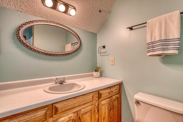 bathroom with vanity, a textured ceiling, toilet, and lofted ceiling