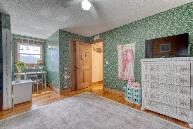 bedroom with hardwood / wood-style flooring, ceiling fan, and a textured ceiling