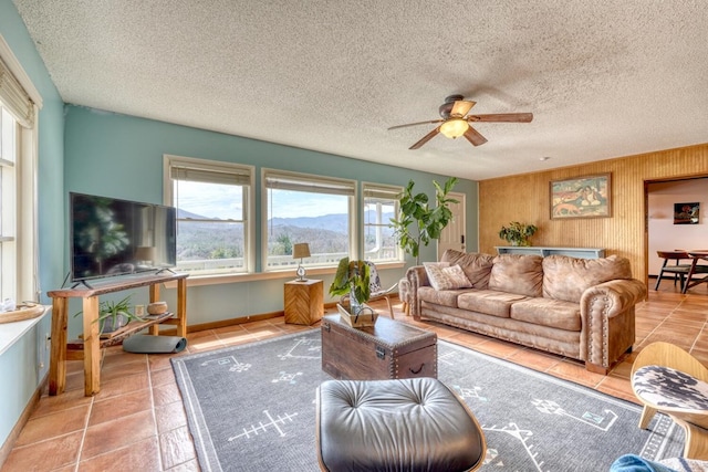 living room with a textured ceiling, tile patterned floors, ceiling fan, and wood walls