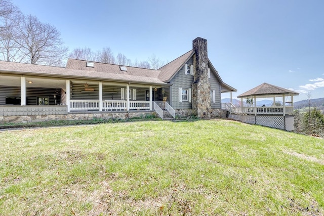 rear view of house featuring a gazebo, a porch, and a lawn