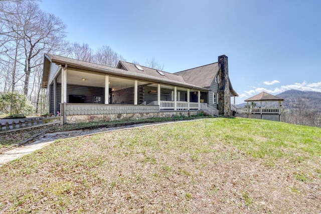 rear view of house with covered porch and a lawn