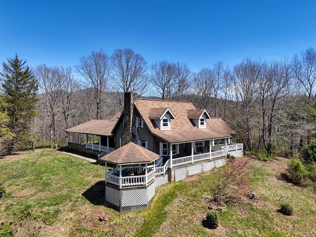 rear view of house featuring a yard and a porch