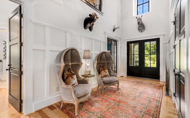 interior space featuring a high ceiling, light hardwood / wood-style flooring, and french doors