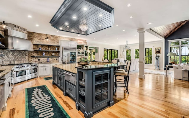 kitchen with white cabinets, a breakfast bar, an island with sink, and light hardwood / wood-style floors