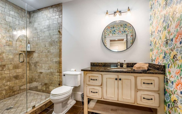 bathroom featuring toilet, a shower with door, tile floors, and vanity