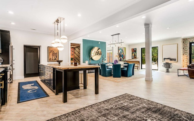 kitchen with hanging light fixtures, a kitchen island, a kitchen bar, light stone countertops, and ornate columns