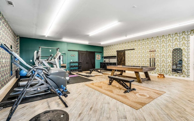 exercise area featuring a barn door, light hardwood / wood-style floors, and billiards