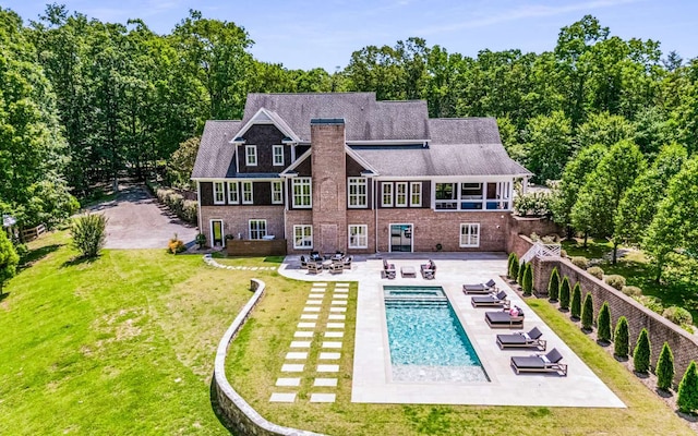 back of property with a fenced in pool, a lawn, and a patio area