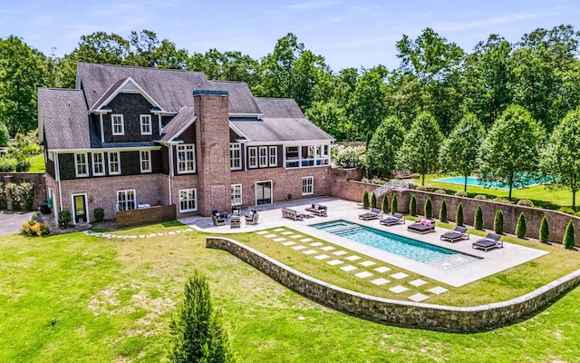 rear view of house featuring a patio, a yard, and a swimming pool with hot tub