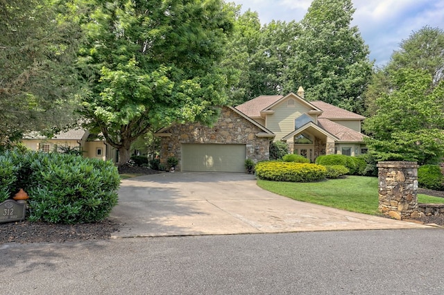 view of front facade with driveway, stone siding, an attached garage, and a front yard