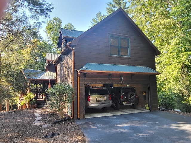 view of side of property with metal roof and driveway