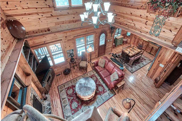 living area featuring wood walls, high vaulted ceiling, wood finished floors, and an inviting chandelier