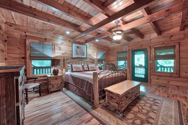 bedroom featuring wooden ceiling, wood walls, light wood-style floors, and beamed ceiling