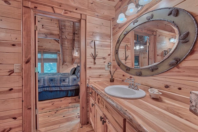 ensuite bathroom with wood finished floors, wood walls, vanity, and ensuite bathroom