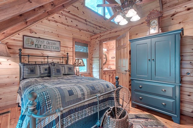 bedroom with wood walls, vaulted ceiling, wood finished floors, and ensuite bathroom