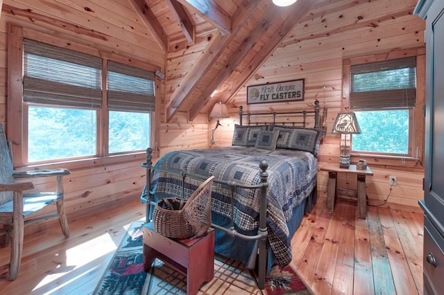 bedroom with lofted ceiling, light wood-style flooring, wooden walls, and multiple windows