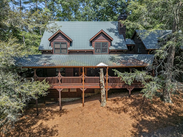 view of front of house with a deck, a chimney, and metal roof