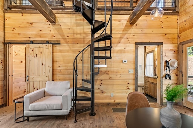 living area featuring wood-type flooring, wooden walls, and beamed ceiling