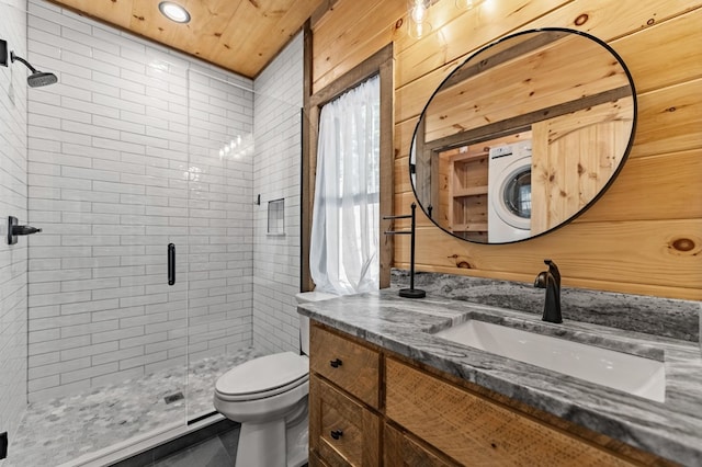 bathroom featuring wood walls, walk in shower, toilet, washer / dryer, and vanity