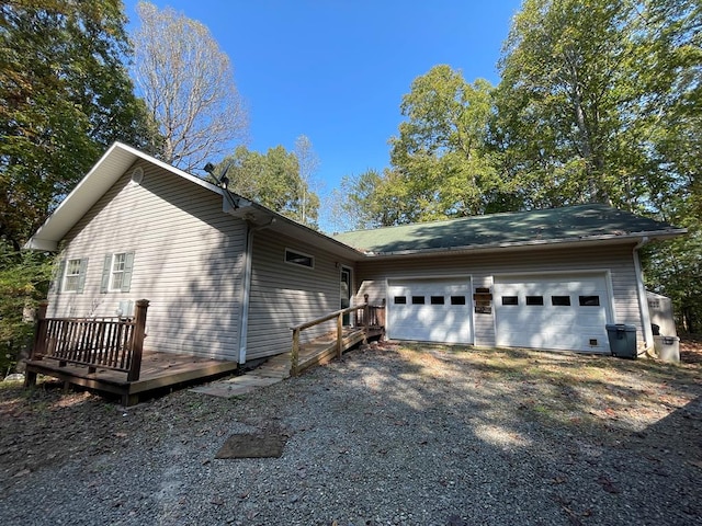 view of side of home featuring gravel driveway, an attached garage, and a deck