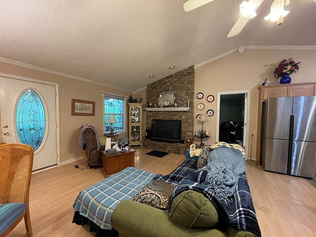 living area with lofted ceiling, light wood-style floors, a fireplace, and ornamental molding