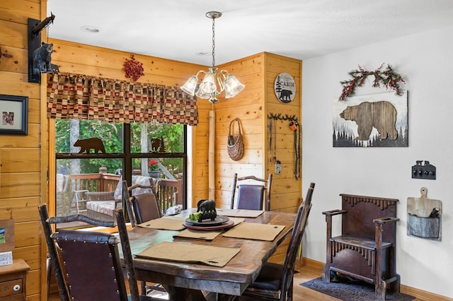 dining space with wood-type flooring, an inviting chandelier, and wood walls